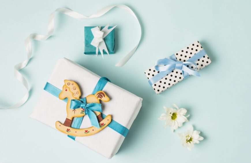 rocking-horse-toy-with-gift-boxes-flowers-ribbon-blue-backdrop